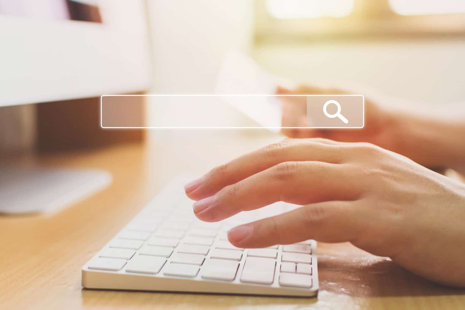 Close up of hands writing SEO content on a keyboard with a search bar imposed over the top